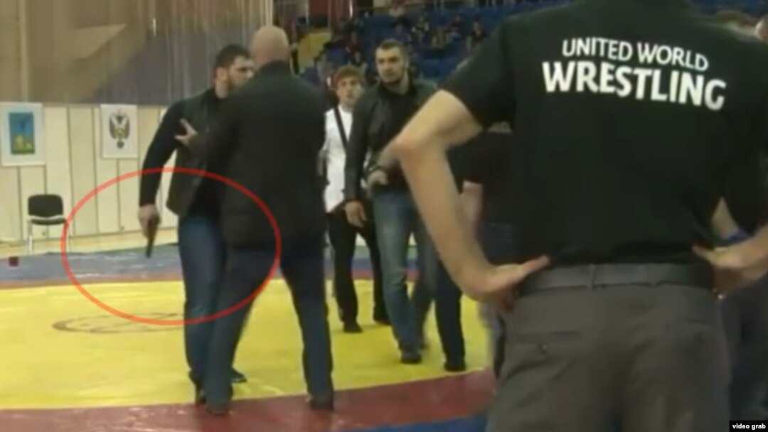 A screen grab from a YouTube video appears to show a man brandishing a gun during a melee that broke out during a wrestling match in Russia.