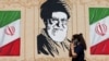 An Iranian woman walks past a wall decorated with the image of late Supreme Leader Ayatollah Ali Khamenei in central Tehran earlier this week. 