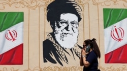 An Iranian woman walks past a wall decorated with the image of late Supreme Leader Ayatollah Ali Khamenei in central Tehran earlier this week. 