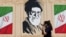 An Iranian woman walks past a wall decorated with the image of late Supreme Leader Ayatollah Ali Khamenei in central Tehran earlier this week. 