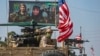 FILE: A U.S. armored vehicle drives past a billboard for the Syrian Kurdish Women's Protection Units (YPJ), during a patrol of the Syrian northeastern town of Qahtaniyah at the border with Turkey, in October.