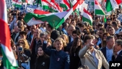 Liderul opoziției maghiare și președintele partidului Tisza (Respect și Libertate), Peter Magyar (în centru), flutură un steag maghiar în timpul unui miting electoral organizat de partidul său la Budapesta, pe 15 martie.