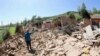 A woman points at her collapsed home after a strong earthquake rocked Gansu Province. 