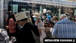 Maszkot viselő utasok szállnak fel egy vonatra a jeruzsálemi Mahane Yehuda piaci állomáson, egy nappal a Rosh-Hashana (zsidó újév) 2020. szeptember 17-én