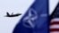 The U.S. and NATO flags flutter as a U.S. Air Force F-22 Raptor fighter jet flies over the military air base in Siauliai, Lithuania, on April 27.