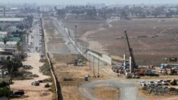 Люди (справа) работают над прототипом стены Трампа на границе с Мексикой в Сан-Диего, Калифорния. Фотография сделана в Тихуане, Мексика. 3 октября 2017 года.