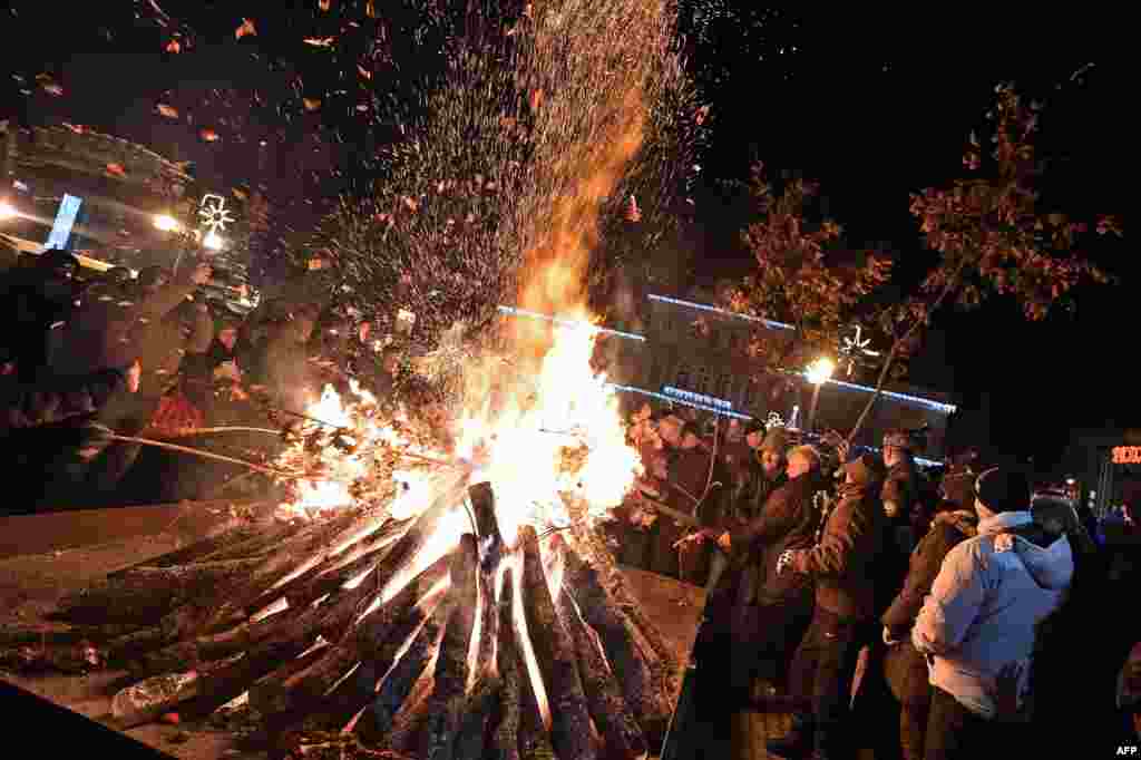 People attend a ceremonial burning of dried oak branches, a Yule log symbol, for Orthodox Christmas Eve in front of a church in Smederevo, 60 kilometers east of Belgrade, Serbia.