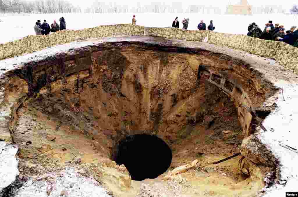 Journalists and military officials from Ukraine, Russia, and the United States inspect a massive crater from a destroyed nuclear missile silo at a military base in Pervomaysk in 1996. Ukraine transferred its last 40 nuclear warheads to Russia that June and officially lost its status as a nuclear power.&nbsp;