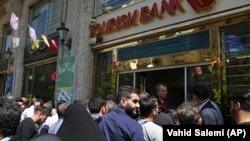 Iranians stand in front of a bank, hoping to buy U.S. dollars at a new official exchange rate announced by the government, in downtown Tehran, April 10, 2018