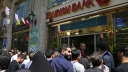 Iranians stand in front of a bank, hoping to buy U.S. dollars at a new official exchange rate announced by the government, in downtown Tehran, April 10, 2018