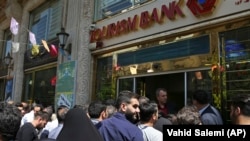 Iranians stand in front of a bank, hoping to buy U.S. dollars at the new official exchange rate announced by the government, in downtown Tehran, April 10, 2018