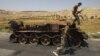 Syrian rebel fighters are pictured next to a burnt-out army tank in the northern town of Atareb, 25 kilometers east of Syria's largest city, Aleppo, on July 31.