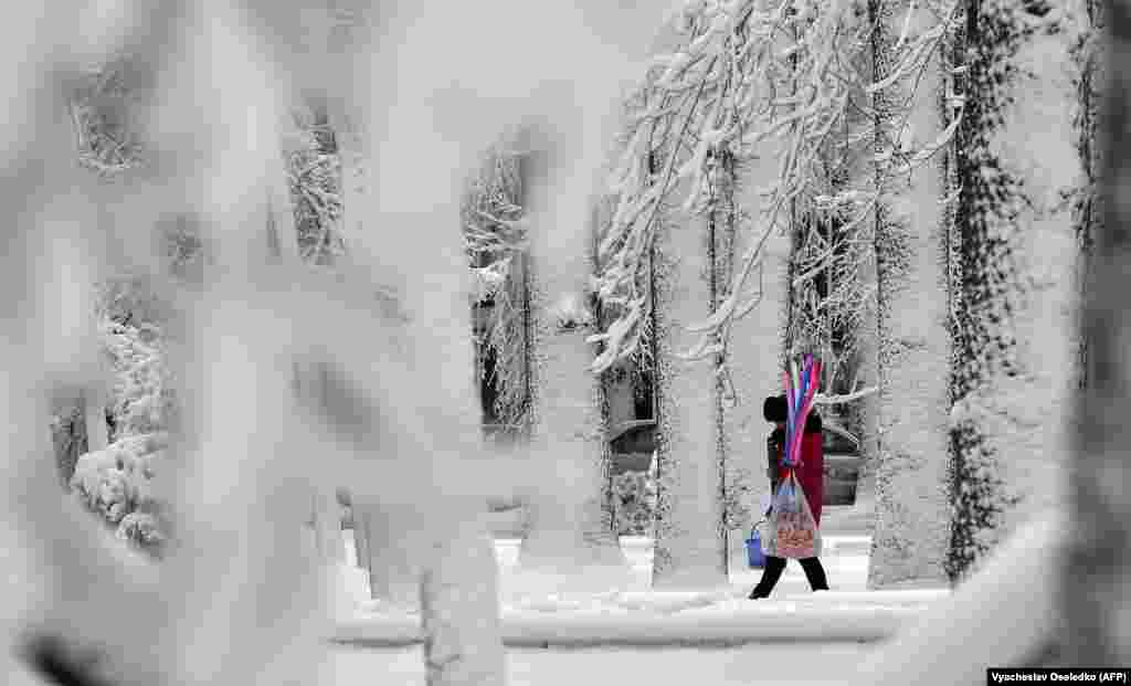 Жанчына з балёнікамі ідзе па засьнежанай вуліцы ў Бішкеку, Кыргызстан. (AFP / Вячаслаў Асяледка)