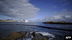 A platform boat carries stones near the cruise liner "Costa Concordia" as rescue and salvage continued as it lay aground off Giglio Island on January 23.