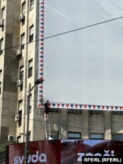Pokušaj da se skine plakat sa Palate Albanija tokom protesta.