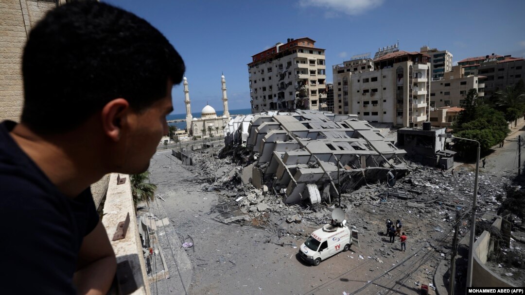 Un palestinian se uită la o clădire distrusă din orașul Gaza, în urma unei serii de atacuri aeriene israeliene asupra Fâșiei Gaza, controlate de Hamas, la începutul zilei de 12 mai 2021. 