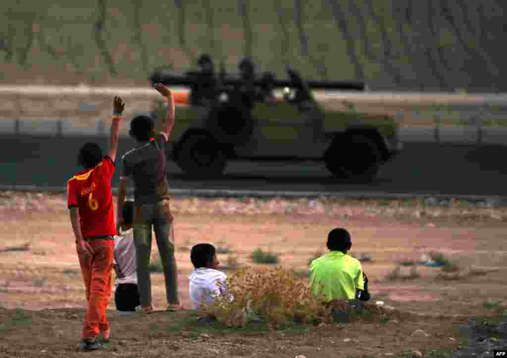 Internally displaced children from the Yazidi community wave to Kurdish Peshmerga forces near Dohuk, the Kurdish region of autonomous Kurdistan in Iraq. (AFP/Ahmad al-Rubaye)