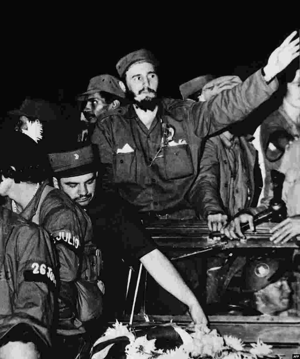 Surrounded by members of his leftist guerrilla movement, Castro (center) waves to crowds in Cienfuegos shortly after ousting Cuban dictator Fulgencio Batista in 1959.&nbsp;