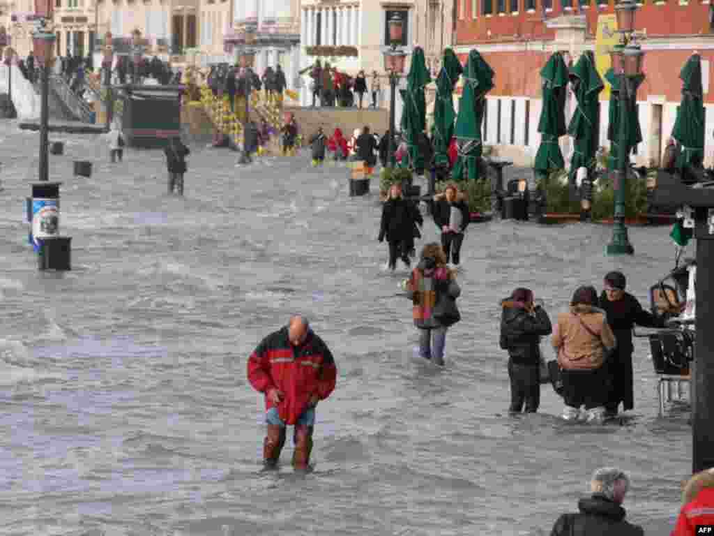 Venice flooding - People walk on a flooded quay of the Grand Canal in Venice during the highest floods for 22 years, 01December 2008 