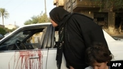 An Iraqi woman looks inside a blood-stained car after an incident in central Baghdad in October 2007.