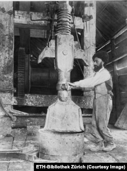 A worker handles an impact tool above a well opening.