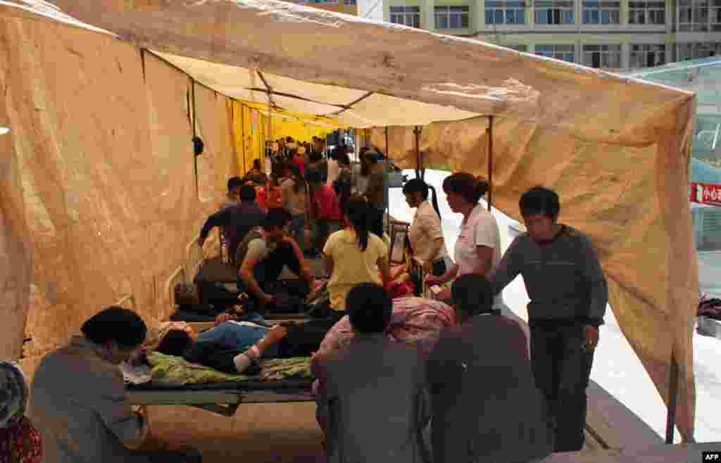 Injured residents of Minxian district in Gansu receive treatment in an emergency tent outside a hospital. 