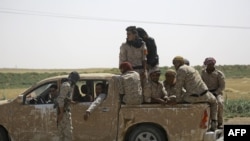 Members of the US-backed Syrian Democratic Forces (SDF) sit in the back of a pick-up truck on the northern outskirts of the Islamic State stronghold of Raqqa. 