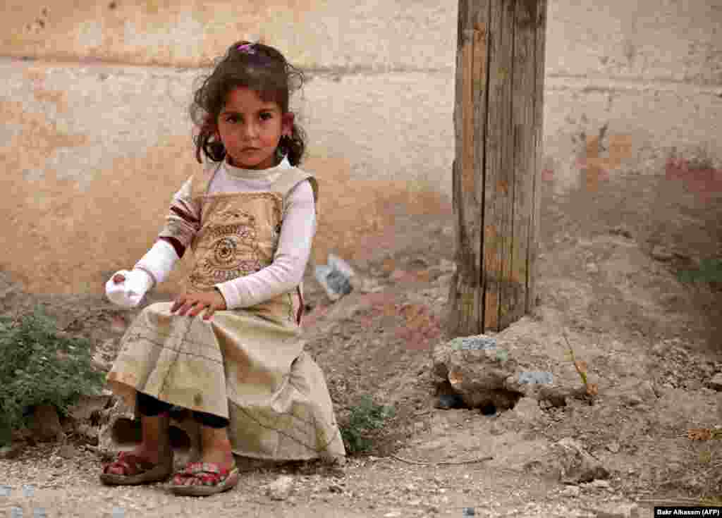 A Syrian girl sits on the side of a road after receiving treatment in the border town of Tal Abyad. (AFP/Bakr Alkasem)