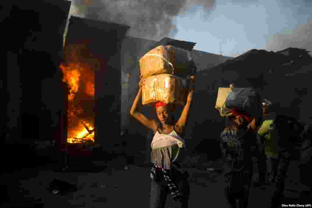 Vendors carry away salvaged merchandise from the burned ruins of a market in Port-au-Prince, Haiti. (AP/Dieu Nalio Chery)