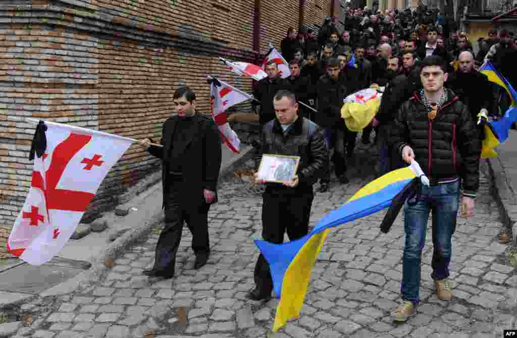 Carrying Georgian and Ukrainian national flags, people take part in the funeral of Dato Kipiani in Tbilisi, Georgia. Kipiani, a Georgian citizen and supporter of the Ukrainian opposition, was shot dead during protest rallies in the Ukrainian capital on February 20. (AFP/Vano Shlamov)