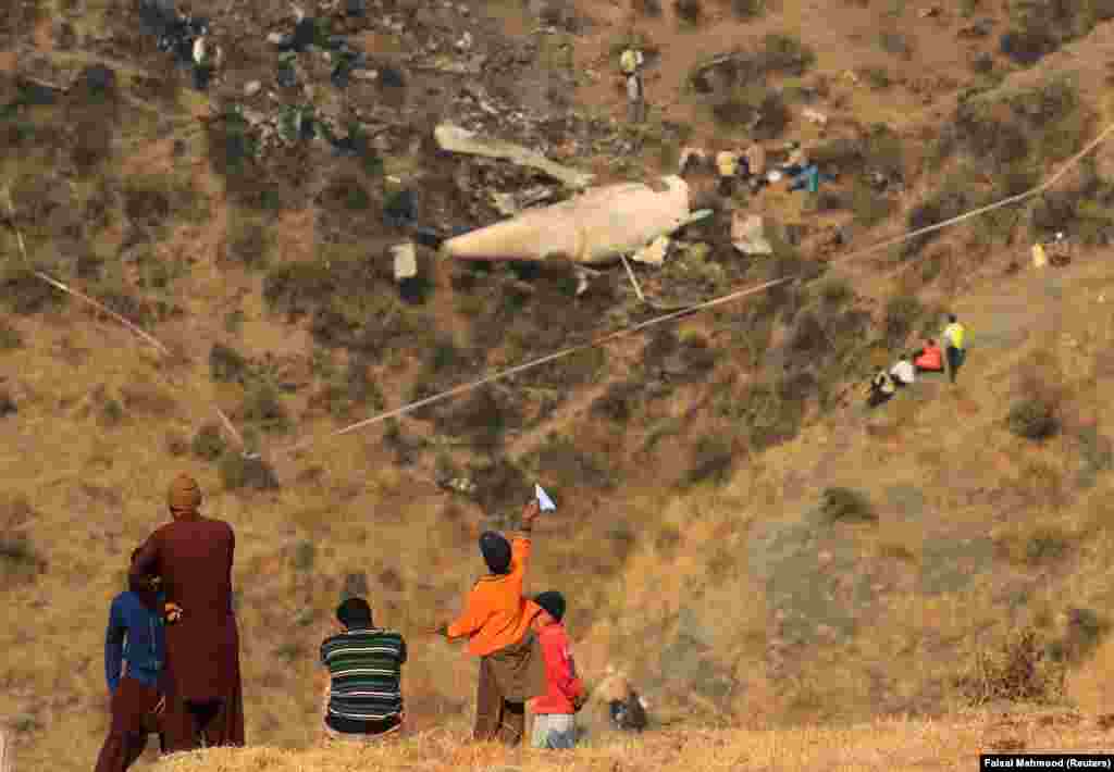 A boy plays with a paper plane near the site of a plane crash in the village of Saddha Batolni near Abbottabad, Pakistan, on December 8. All 47 people on board the plane were killed in the December 7 crash, including Junaid Jamshed, a Pakistani pop star turned Muslim preacher.&nbsp;(Reuters/Faisal Mahmood)