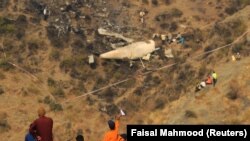 A boy plays with a paper plane near the site of a plane crash in the village of Saddha Batolni near Abbotabad on December 8.