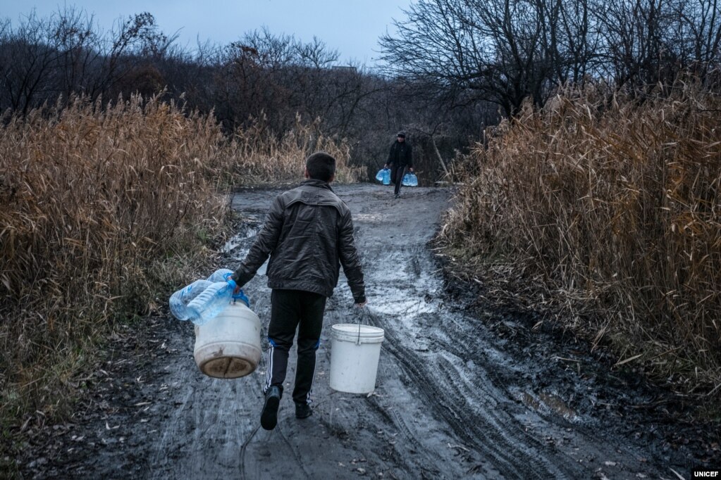 Через постійні обстріли близько 3,6 мільйона жителів Донбасу потерпають від обмеженого доступу до водних ресурсів і належних санітарних умов. ЮНІСЕФ наголошує, що брак чистої води ставить під загрозу безпечне майбутнє. В особливій групі ризику залишаються близько 500 тисяч дітей у Луганській та Донецькій областях, які потребують налагодження постачання води і гігієнічних умов для уникнення поширення інфекцій. На фото 23-річний Іван несе порожні бутилі, щоб набрати води для своєї сім&rsquo;ї, у якій дев&rsquo;ятеро братів і сестер. Сім&rsquo;я живе у Торецьку на Донеччині. Тут часто трапляються тривалі перебої з водопостачанням через пошкодження водопроводу внаслідок обстрілів. Навіть у ті короткі періоди, коли вода є, сім&rsquo;ї її не вистачає. Тому питну воду беруть із місцевого джерела. У місяці, коли вода була повністю відключена, у черзі до джерела люди стояли довгі години.