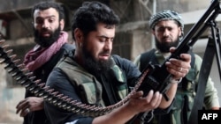 Syria -- A rebel fighter loads his machine gun during fightings with regime forces in the Sheikh Maqsoud neighborhood of Aleppo, 01Apr2013