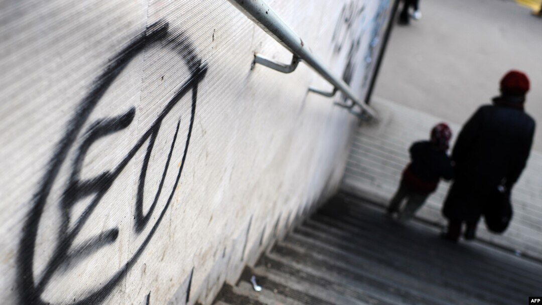 Pedestrians walk past anti-EU graffiti in downtown Belgrade.