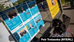 У стенда с листовками с изображением президента Казахстана Касым-Жомарта Токаева, пожимающего руку бывшему президенту страны Нурсултану Назарбаеву. Алматы, 15 мая 2019 года.