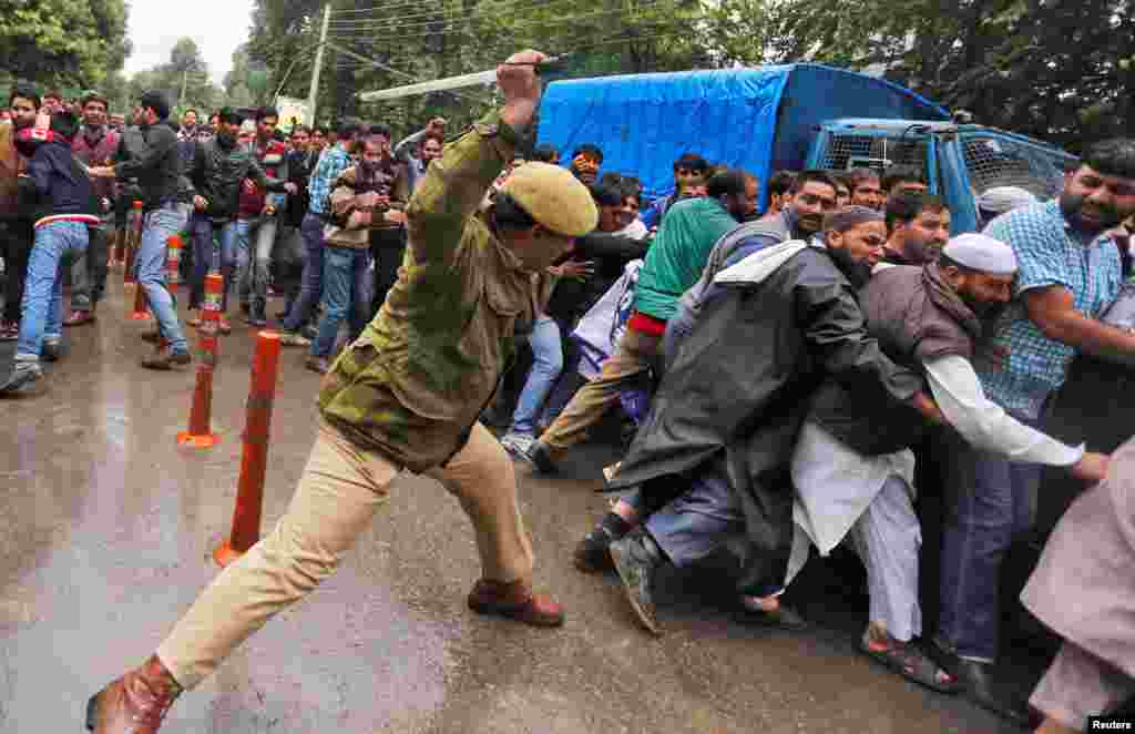 An Indian policeman uses a baton to disperse demonstrators during a protest by government employees demanding reported wage arrears and the regularization of their temporary jobs. (Reuters/Danish Ismail)