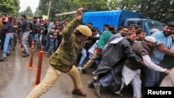 An Indian policeman uses a baton to disperse demonstrators during a protest by government employees demanding their long pending arrears and a regularisation of their temporary jobs, according to protesters, in Srinagar, on May 24.