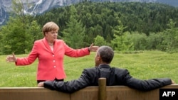 German Chancellor Angela Merkel (left) gestures while chatting with U.S. President Barack Obama sitting on a bench outside the Elmau Castle after a working session of a G7 summit near Garmisch-Partenkirchen on June 8.