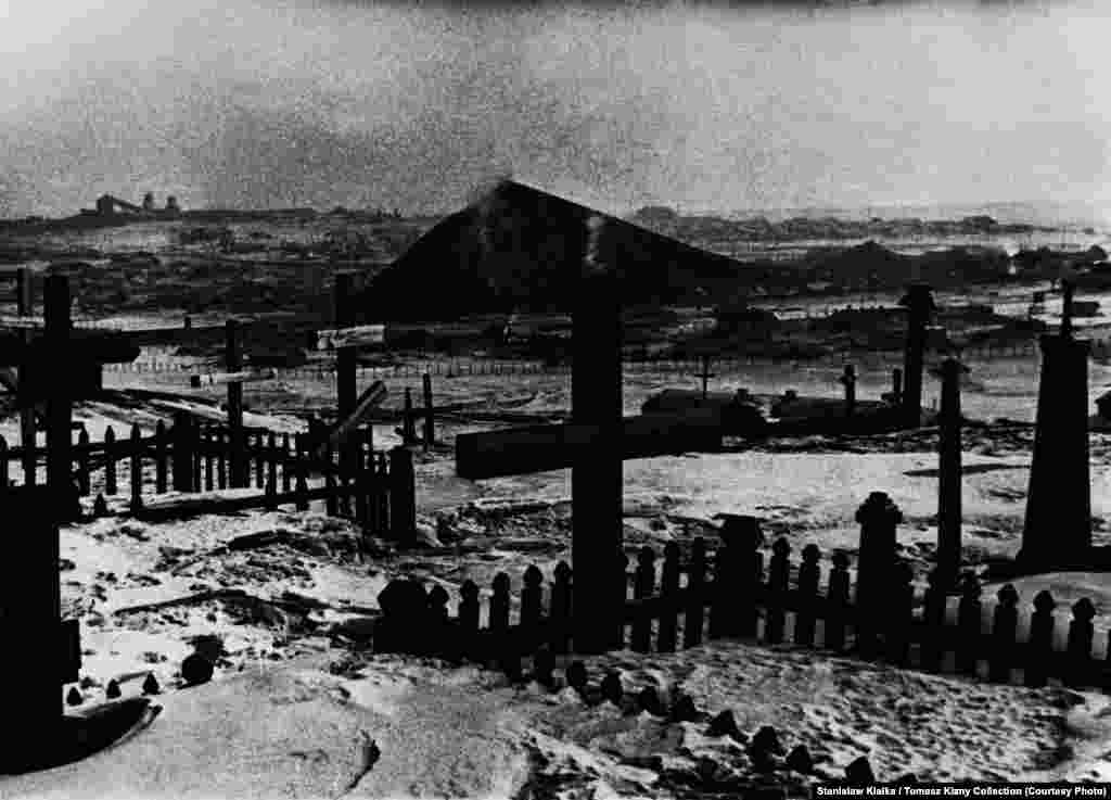 An undated photo showing a cemetery for prisoners and exiles with mines visible in the background. Prisoners were buried in the tundra and their grave was marked with a post bearing the dead person&#39;s camp number. After 1956, released prisoners identified the graves and placed crosses marked with their names.