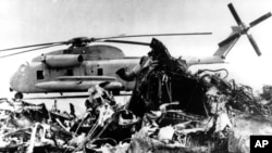 The remains of a burned-out U.S. helicopter lies in front of an abandoned chopper in the eastern desert region of Iran Saturday April 27, 1980, one day after the aborted American Commando raid to free the U.S. embassy hostages. (AP Photo)