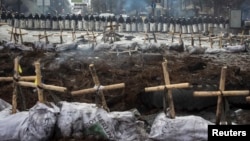 Арнайы жасақ шеру кезінде қаза тапқан және жоғалған адамдарға қойылған белгілердің ар жағында тұр. Киев, 11 ақпан 2014 жыл.