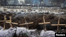 Near the barricades in Kyiv, riot police stand behind crosses installed by anti-government protesters in memory of the people who have died and went missing.