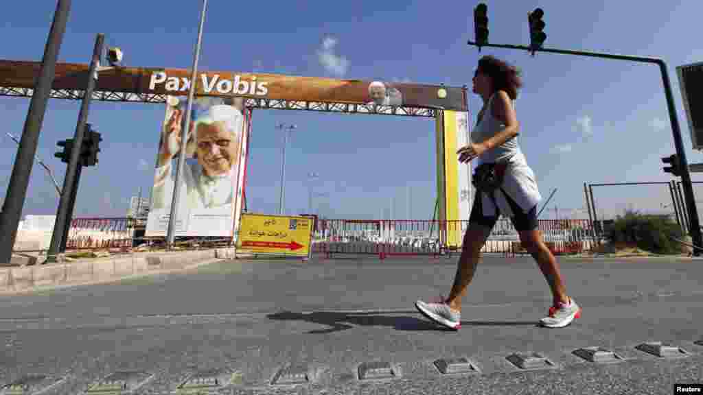 A woman walks by a poster of Pope Benedict XVI before the Roman Catholic pontiff&#39;s visit to Lebanon. (Reuters/Jamal Saidi)