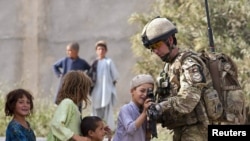 A British Army Major shows his rifle to Afghan children during a patrol near Lashkar Gah, the capital of Helmand Province.