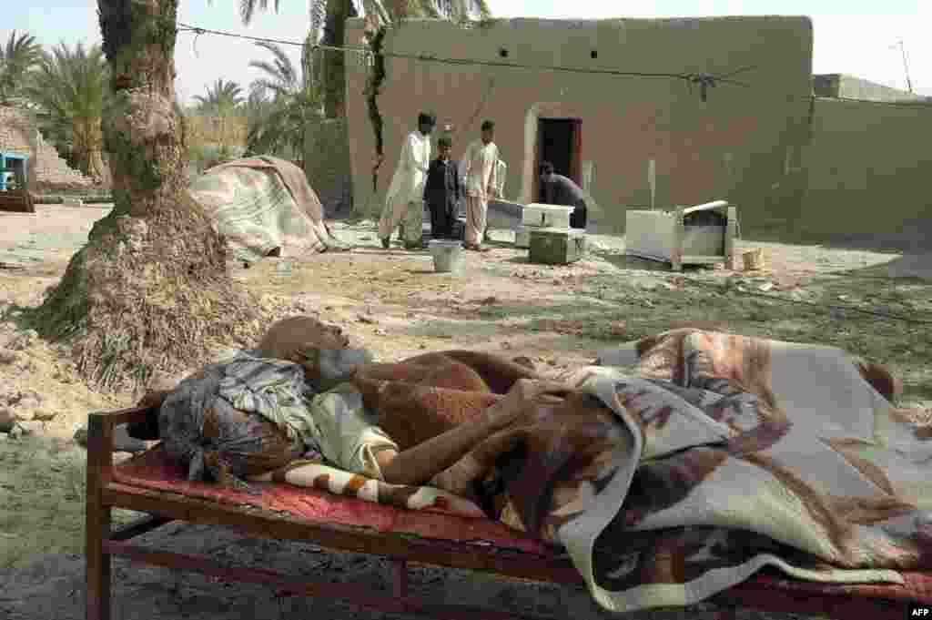An elderly earthquake survivor rests on a "charpai" (wooden bed) outside his damaged mud house in the Mashkail area of southwest Balochistan Province. ( AFP/Banaras Khan)