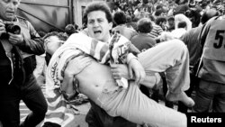 «Ливерпуль» (Англия) мен «Ювентус» (Италия) командаларының ойыны кезіндегі тәртіпсіздік салдарынан зардап шеккен көрерменді Хейсел стадионынан көтеріп алып шығып келе жатқан адам. Брюссель, 29 мамыр 1985 жыл.