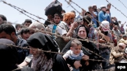 Беженцы на сирийской стороне пограничного перехода возле Акчакале (Турция) 10 июня 2015 