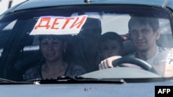 Люди в автомобиле, на лобовом стекле которого - плакат с надписью: "Дети". Иллюстративное фото.