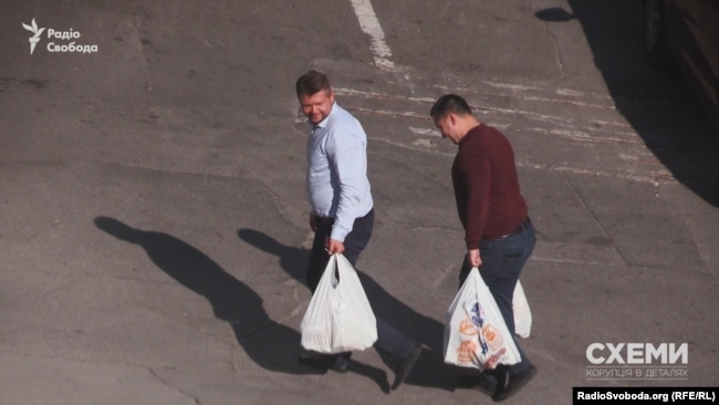 Двоє чоловіків несуть пакети з продуктами до управління СБУ